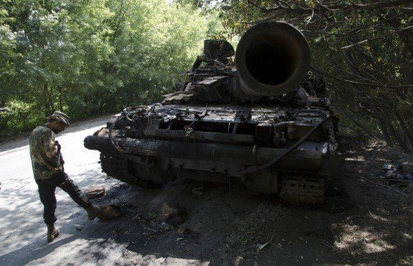 Ein prorussischer Kämpfer vor einem abgeschossenen Panzer der ukrainischen Armee vor Donezk. AP