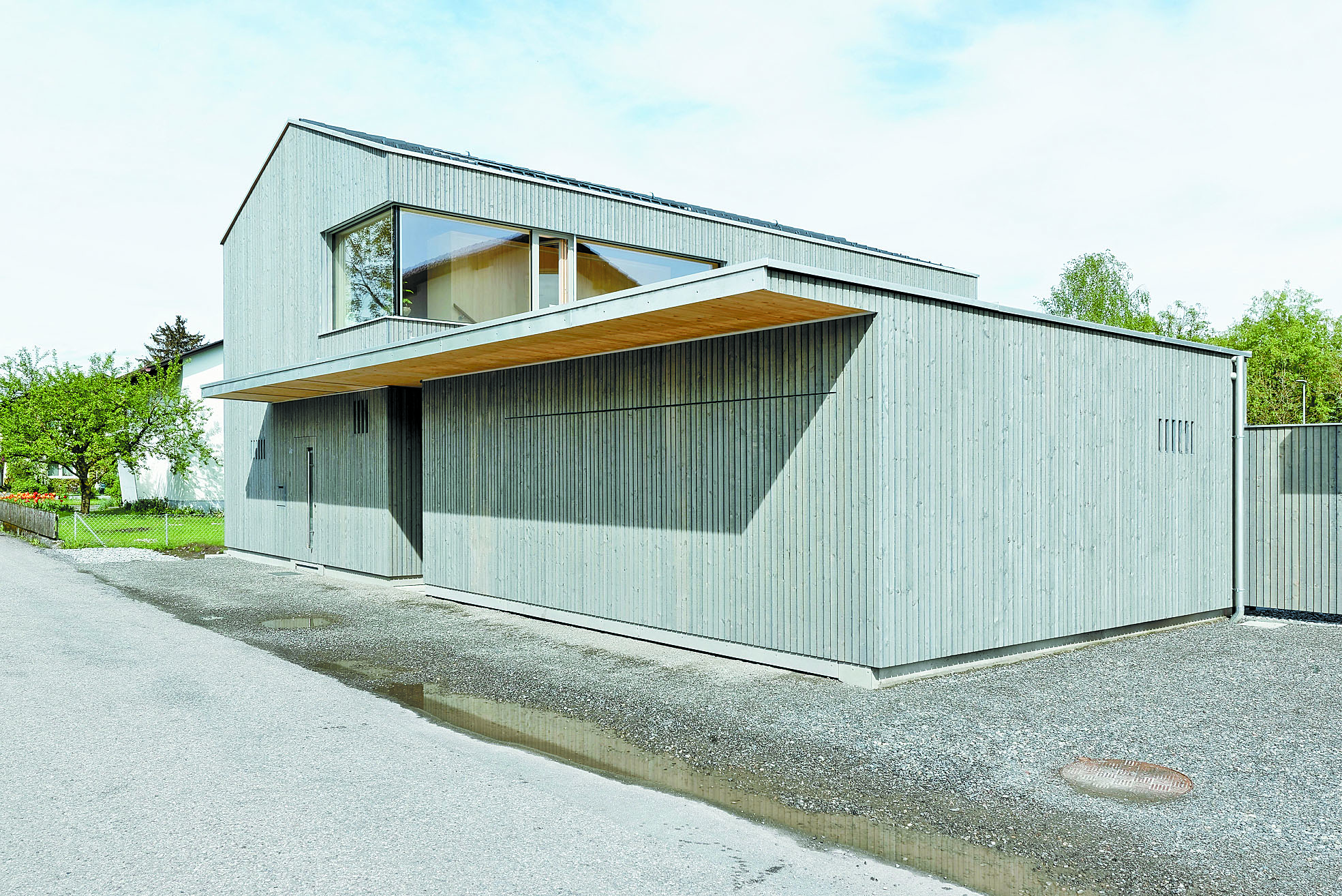Verklammert werden das Haus W und seine Doppelgarage durch ein flaches Dach, das auch die bündig in die Fassade eingelassene Haustüre beschützt. 