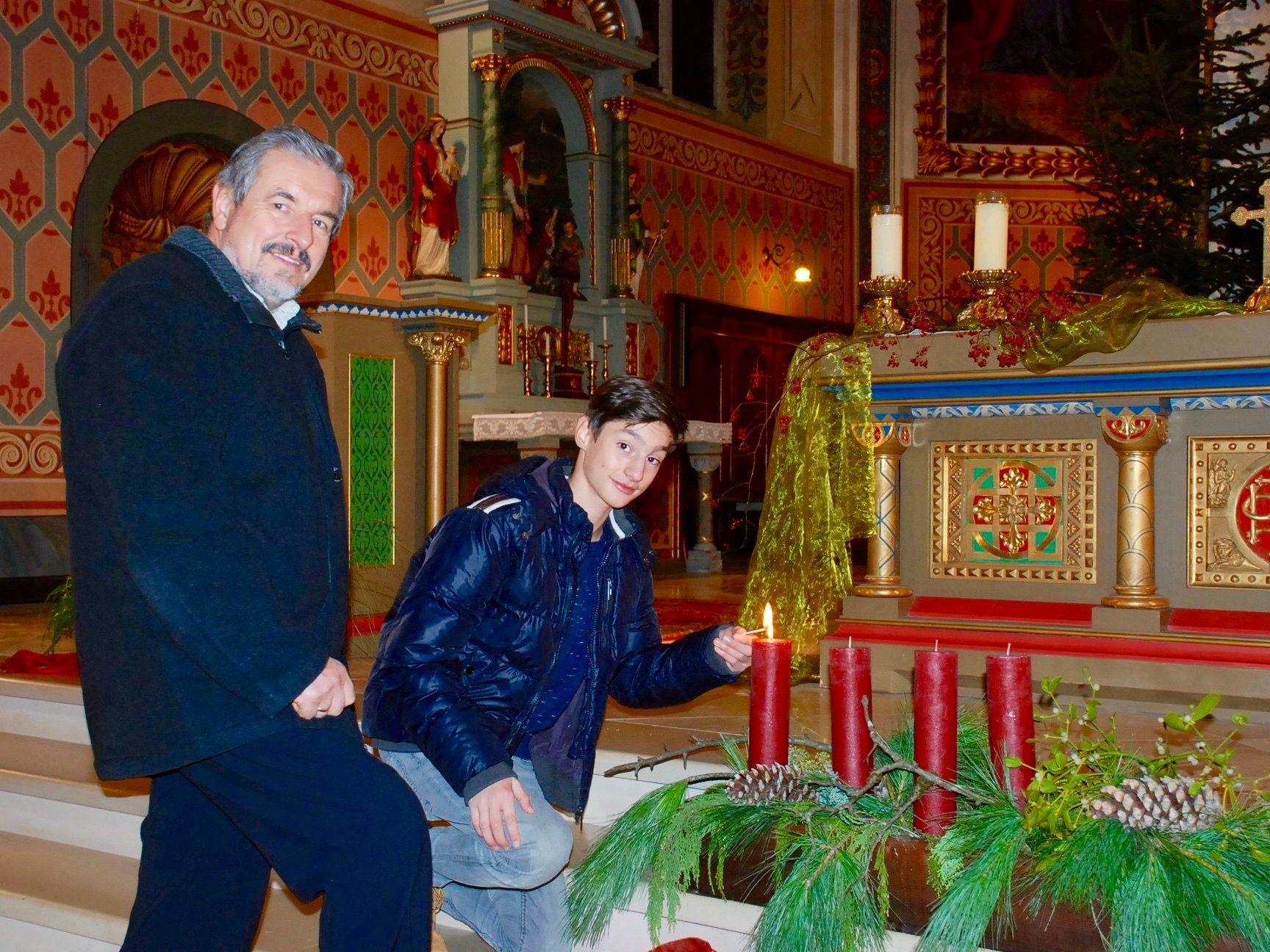 Mesner Kasimir Bors und Ministrant Jannis Fleisch entzündeten Samstagabend die erste Kerze des Adventsgestecks der Pfarrkirche Schruns