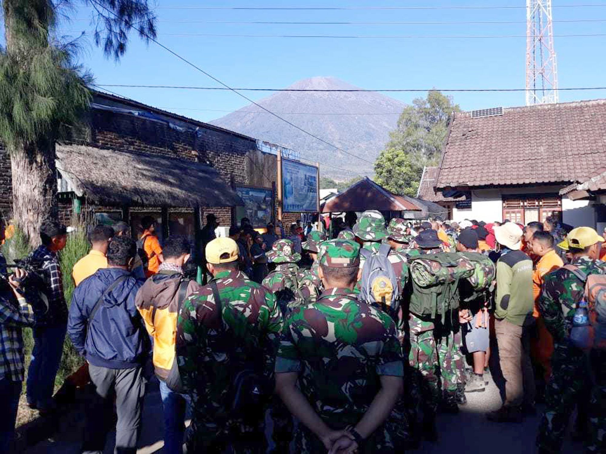 Indonesische Soldaten und Rettungskräfte warten auf Anweisungen. Sie sollen die auf dem Mount Rinjani (im Hintergrund) gefangenen Menschen evakuieren helfen.