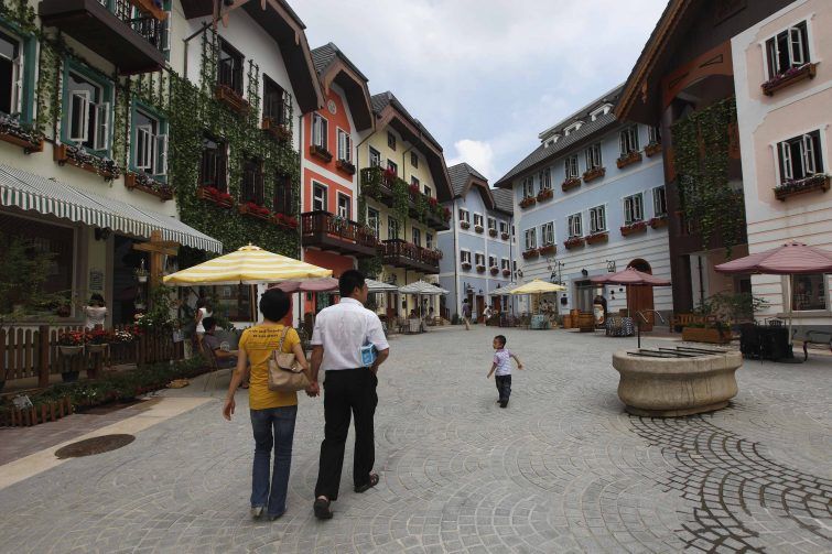 A family walks in the Chinese replica of Austria's UNESCO heritage site, Hallstatt village, in China's southern city of Huizhou in Guangdong province June 1, 2012. Metals and mining company China Minmetals Corporation spent $940 million to build this controversial site and hopes to attract both tourists and property investors alike, according to local newspaper reports. REUTERS/Tyrone Siu (CHINA - Tags: BUSINESS SOCIETY TRAVEL) 