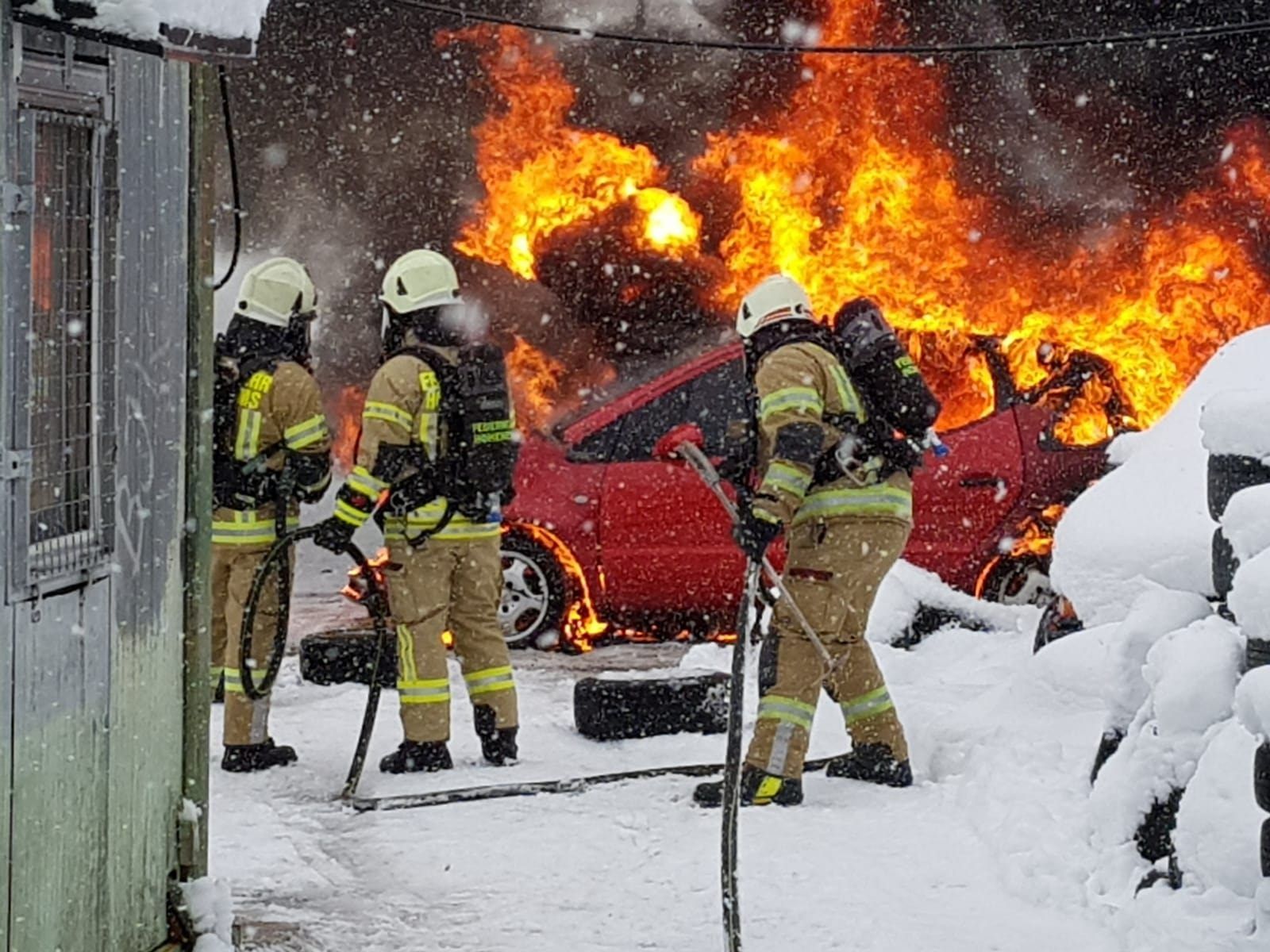 Feuerwehrleute löschen einen brennenden Pkw.