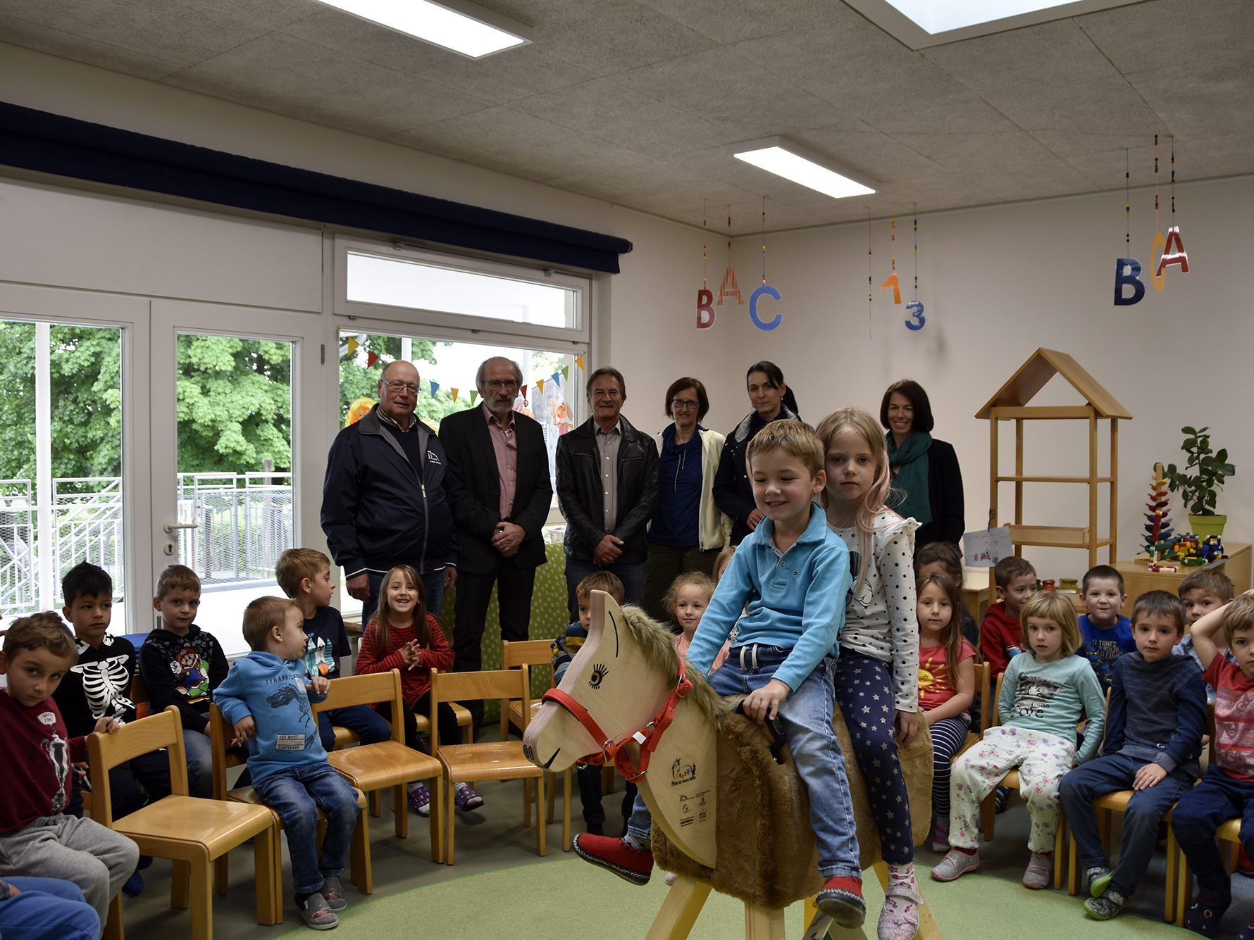 : Das neue Holzpferd im Kindergarten mit den Mitgliedern des Sponsorvereins im Hintergrund (v.l:) Peter Meusburger, Udo Hatzl, Joachim Ess, Alexandra Ludescher-Biber, Sabine Bergner mit Kindergartenleiterin Birgit Burger.