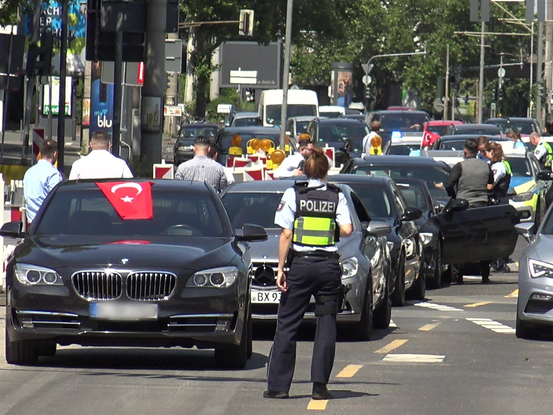 ine Polizistin steht vor den Fahrzeugen eines türkischen Hochzeutskorsos ine Polizistin steht vor den Fahrzeugen eines türkischen Hochzeutskorsos