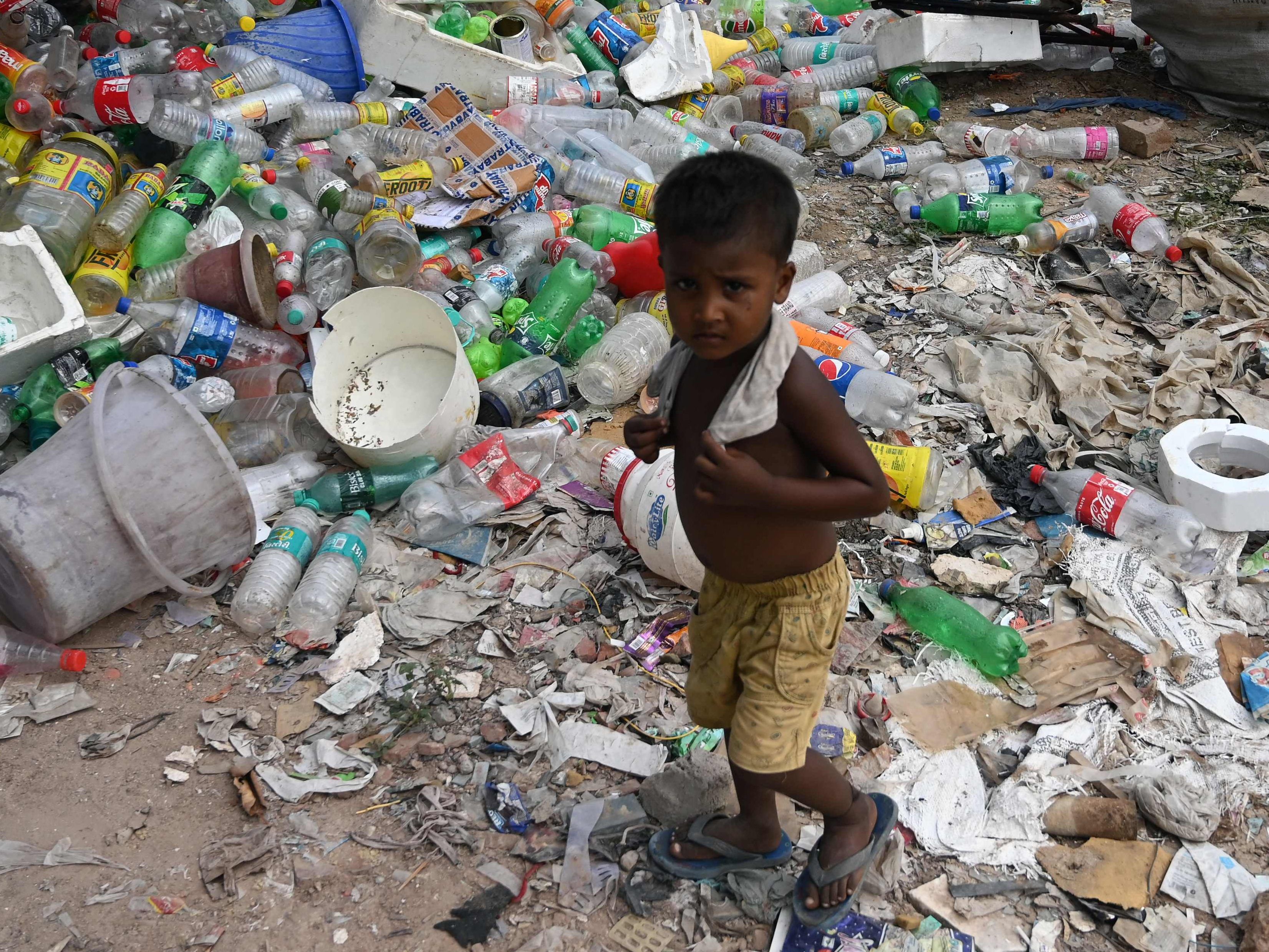 Ein Kind in New Delhi umzingelt von Plastikmüll. Ein Kind in New Delhi umzingelt von Plastikmüll.