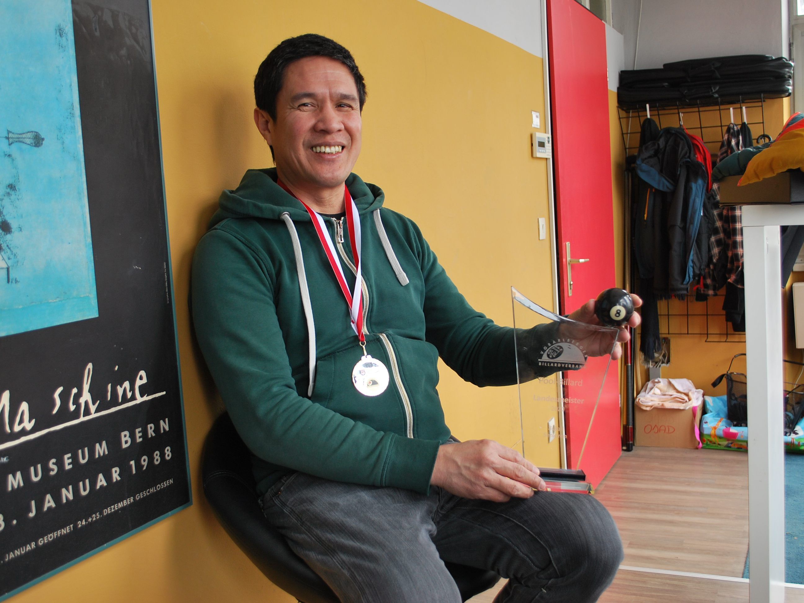 Richard De Guzman zeigt stolz seine Goldmedaille und die Trophäe.