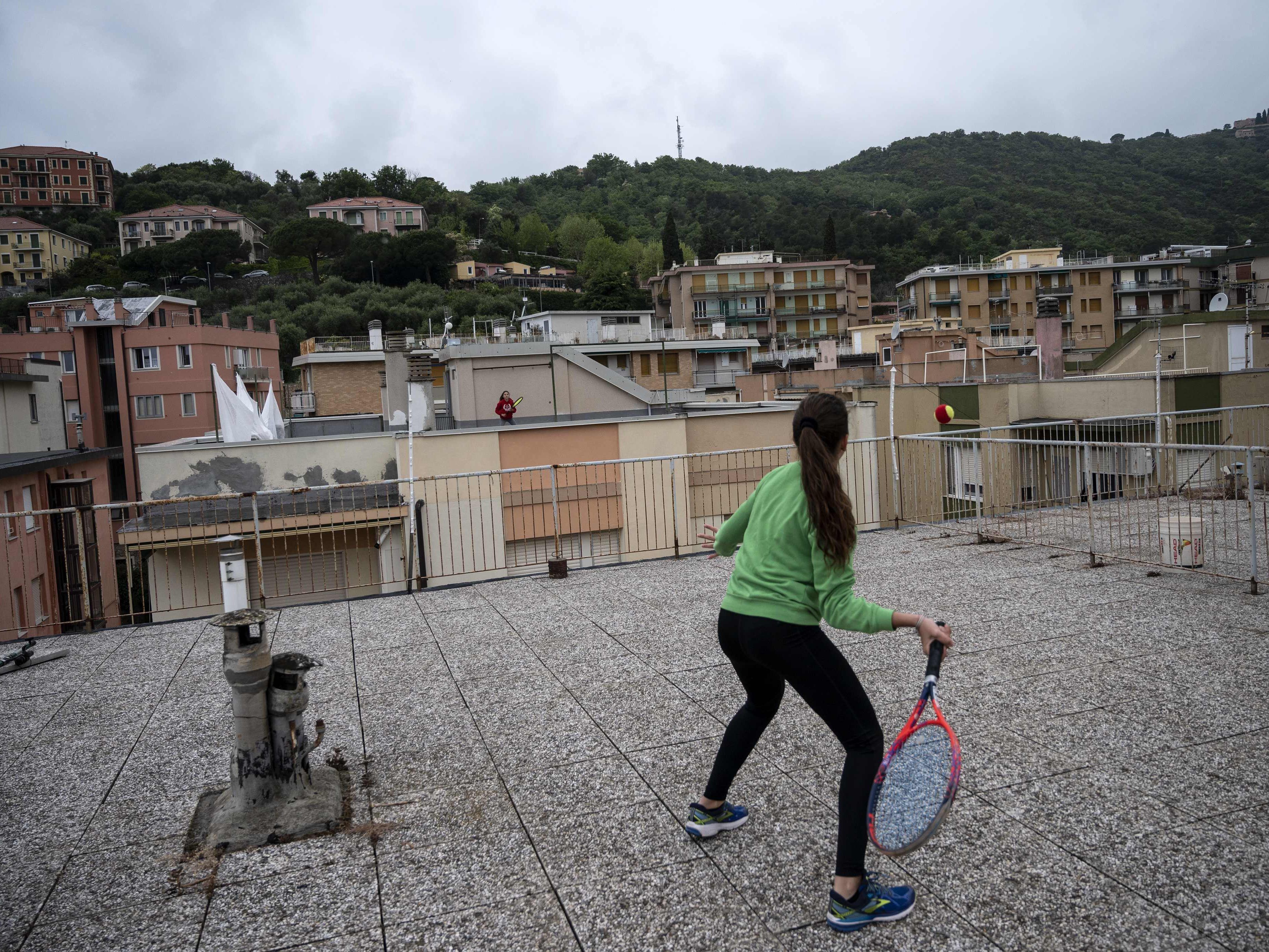 In Italien spiele zwei Mädchen über Dächer hinweg Tennis, um so die Gesetze nicht zu verletzen. In Italien spiele zwei Mädchen über Dächer hinweg Tennis, um so die Gesetze nicht zu verletzen.
