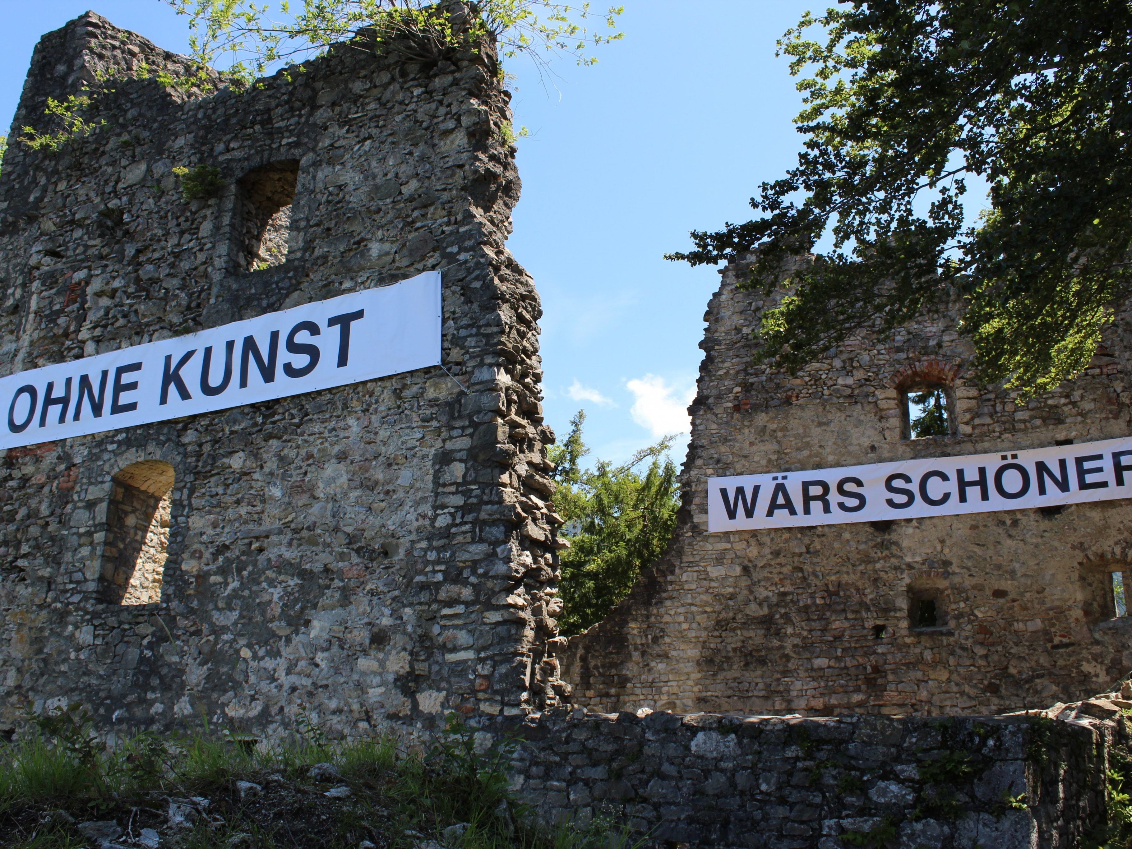 Auf Banner proklamiert Peter Wehinger den Slogan OHNE KUNST WÄRS SCHÖNER.