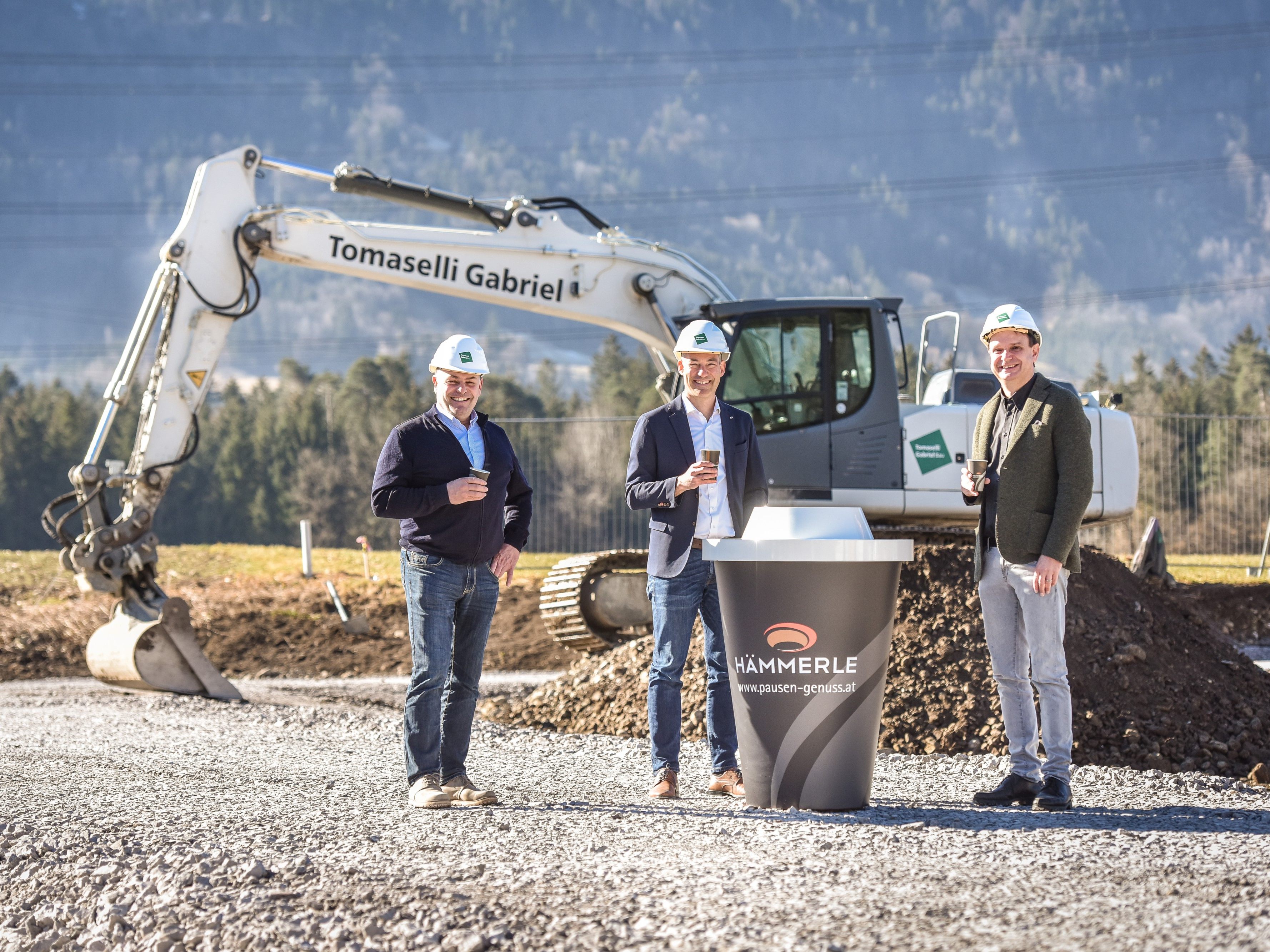 Martin Konzet, Bürgermeister von Bludesch, Markus Hämmerle, Geschäftsführer von Hämmerle Kaffee, und Philipp Tomaselli, Geschäftsführer von Tomaselli Gabriel Bau, freuen sich über den Baubeginn und genießen dabei einen Becher Hämmerle-Kaffee.