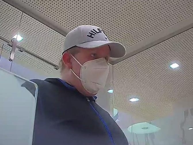 Der Bankräuber drohte in der Bank mit einer Waffe.
