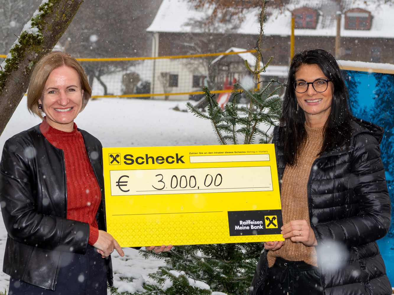 Julia Brunner-Böhler und Karin Mäser bei der Scheckübergabe im winterlichen Vorarlberger Kinderdorf.