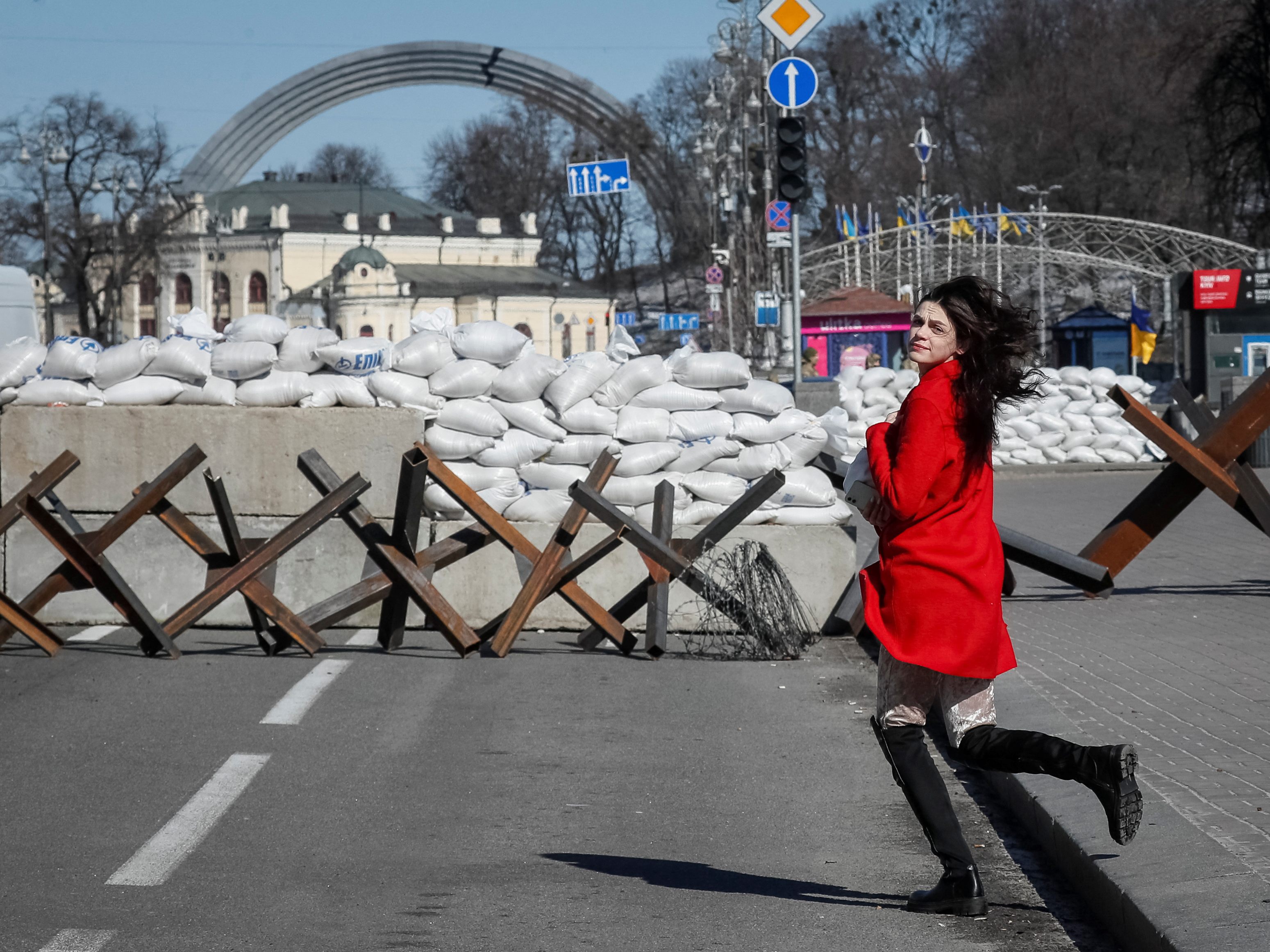 Eine Frau rennt über die Straße vor einer Anti-Panzer-Konstruktion in Kiew.