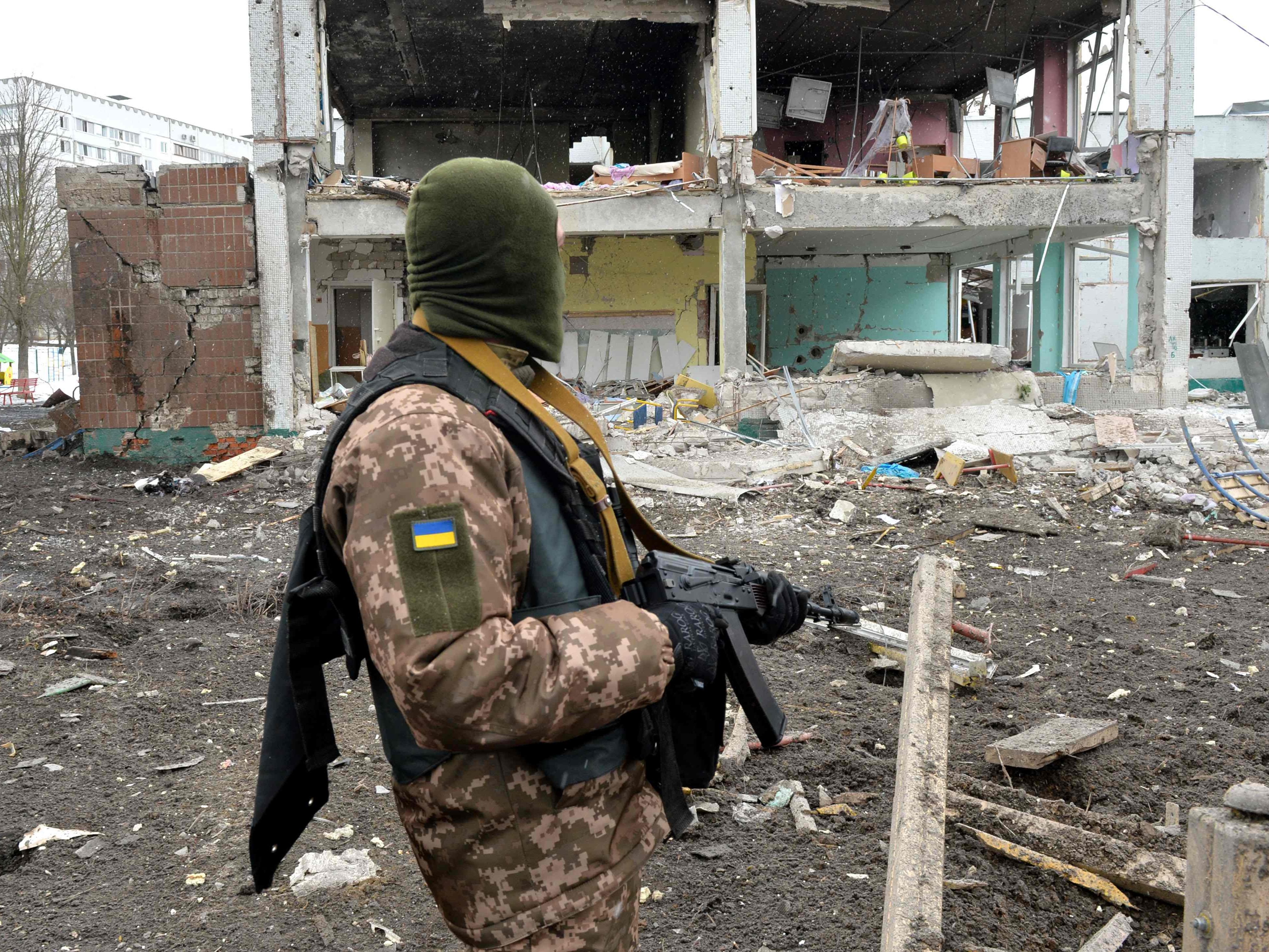 Ein Mitglied der Ukrainian Territorial Defence Forces schaut auf die Zerstörung in Charkiw ausgelöst durch russischen Beschuss. Ein Mitglied der Ukrainian Territorial Defence Forces schaut auf die Zerstörung in Charkiw ausgelöst durch russischen Beschuss.