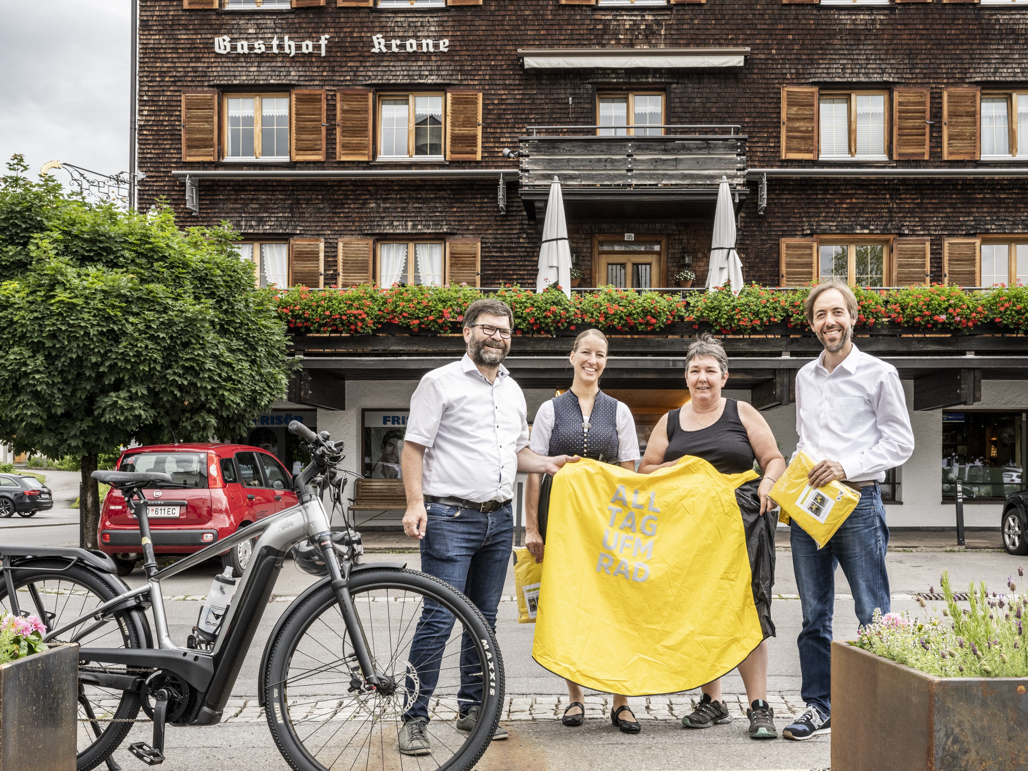 Bürgermeister Gerhard Beer und Kronenwirt Dietmar Nußbaumer bei der Übergabe der Regenponchos an die Jobradlerinnen Angelika Garcia-Lopez und Emanuela Falschlunger.