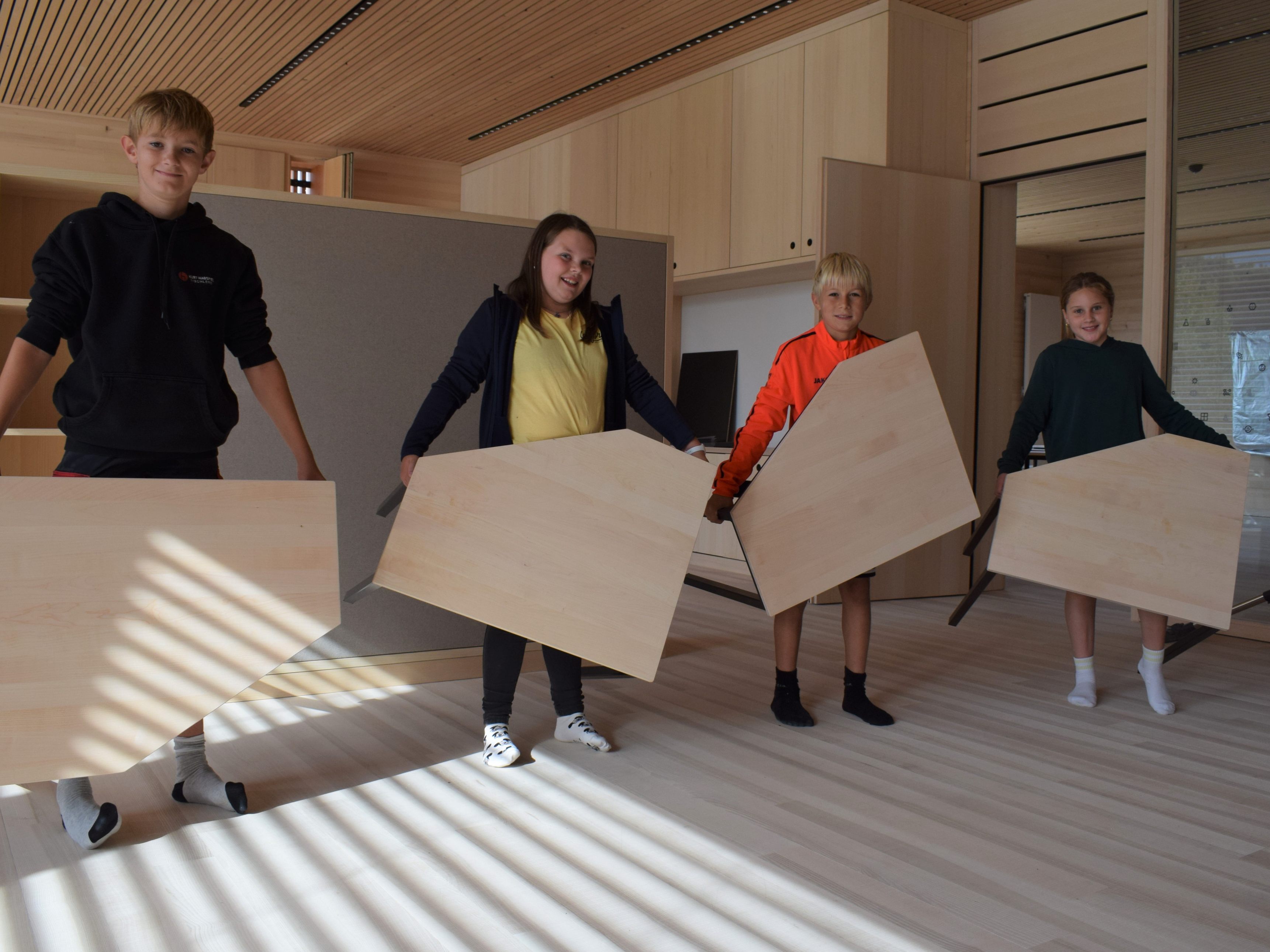 Hittisauer Mittelschüler tragen stolz die neuen Fünfeck-Tische in ihre Klassen.