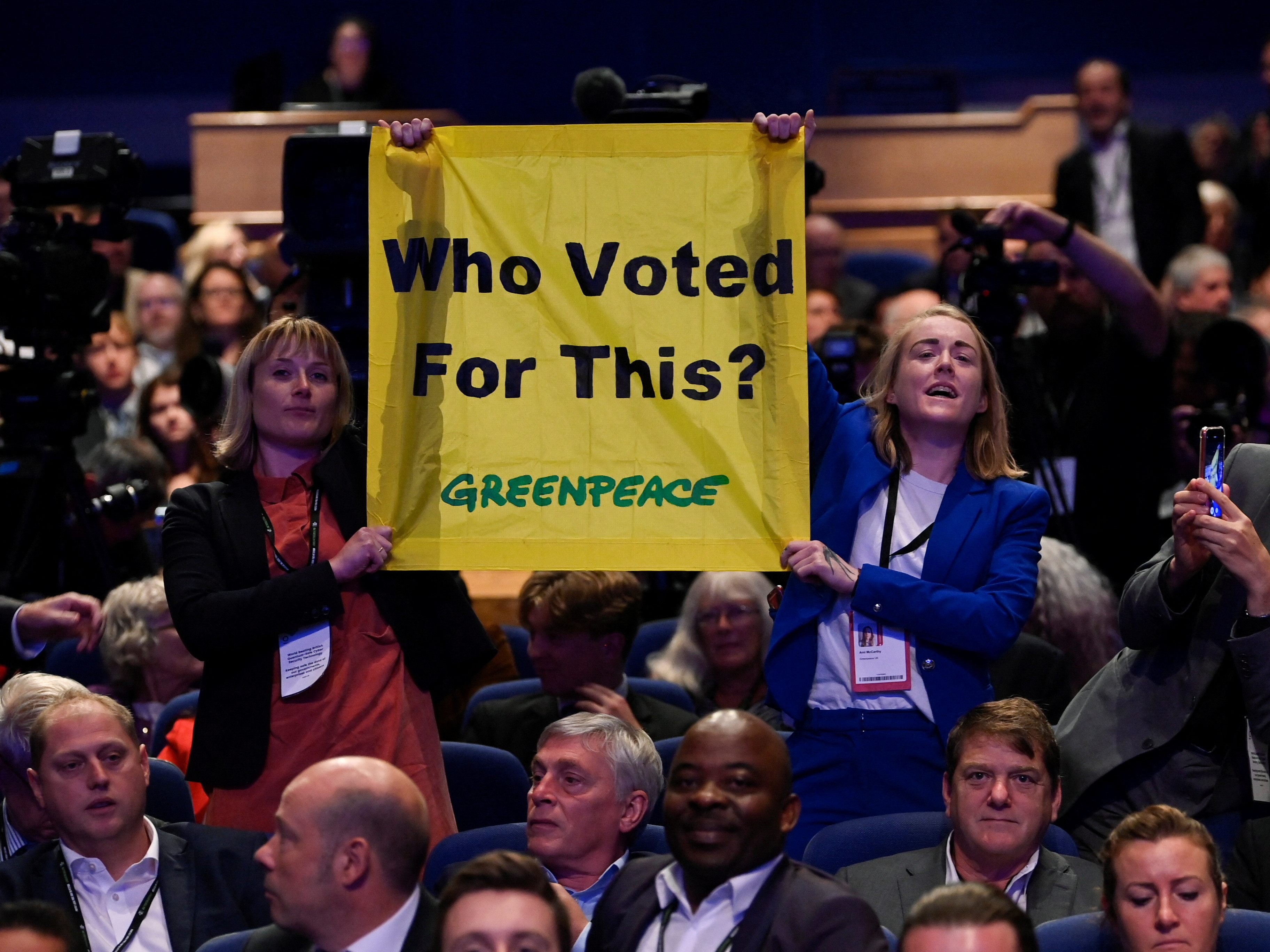 "Who Voted For This", steht auf einem Plakat, das Greenpeace-Mitglieder während einer Truss-Rede halten.
