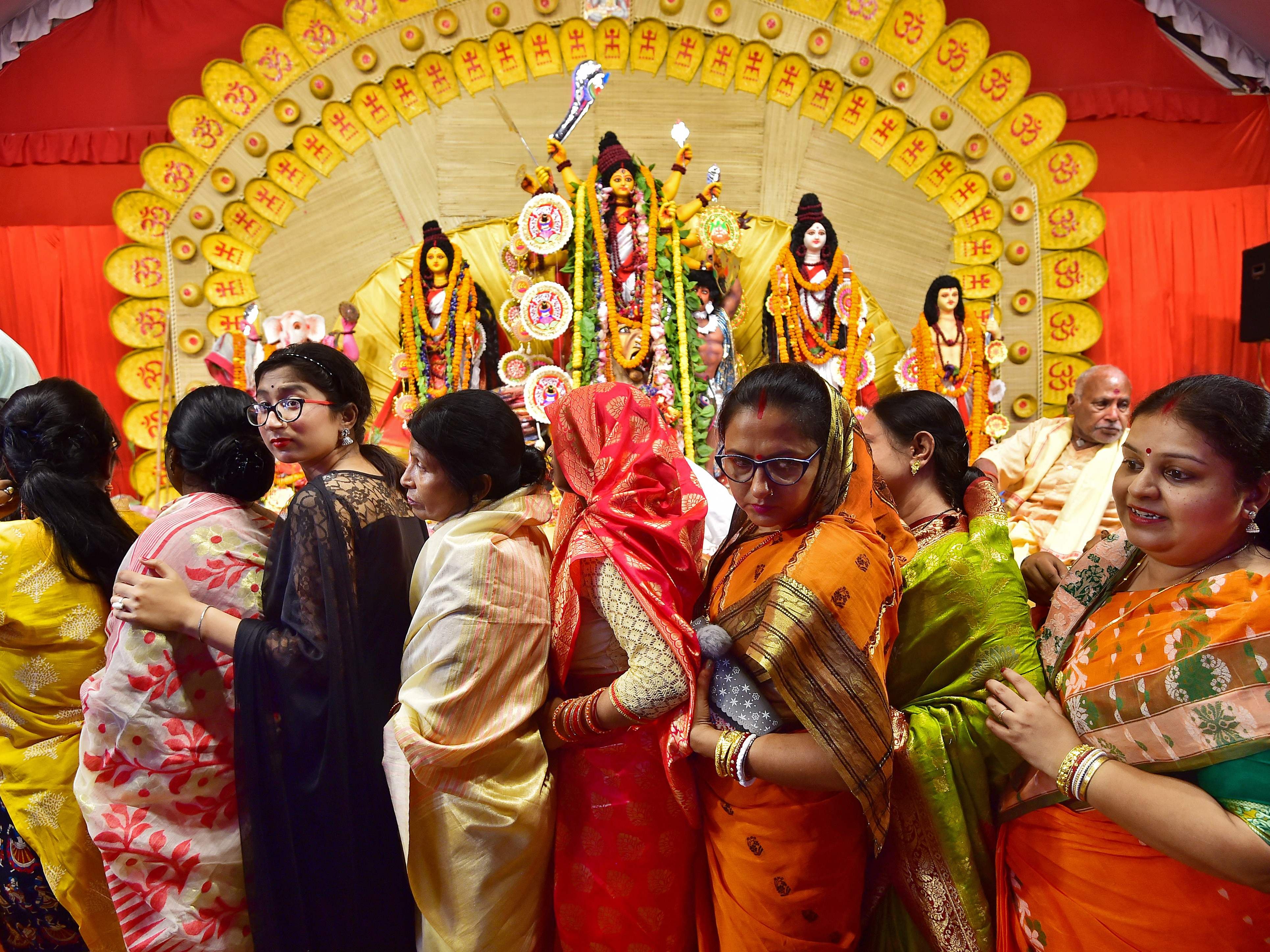 Traditionell gekleidete Inderinnen vor einer Durga-Ikone.