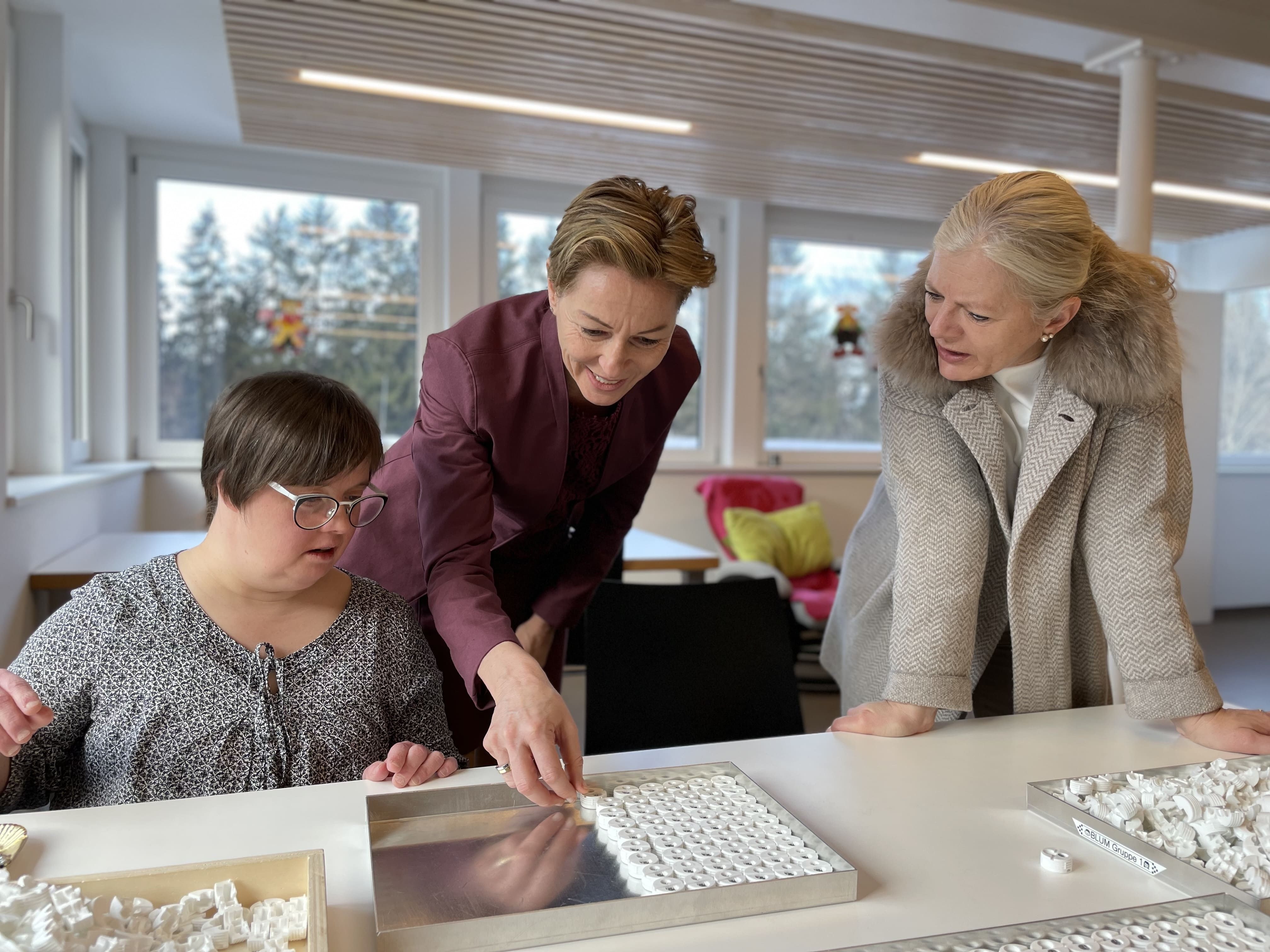 v.li.: Werkstatt-Sprecherin Sandra Mayer erklärt Landesrätin Martina Rüscher und Geschäftsführerin Michaela Wagner-Braito die Auftragsarbeit. v.li.: Werkstatt-Sprecherin Sandra Mayer erklärt Landesrätin Martina Rüscher und Geschäftsführerin Michaela Wagner-Braito die Auftragsarbeit.