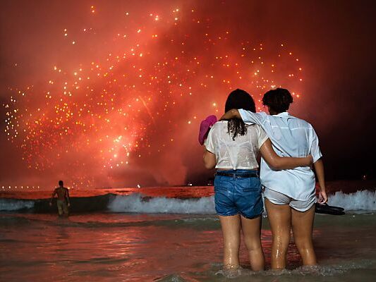 Feuerwerk-Schauen mit den Füßen im Wasser an der Copacabana Feuerwerk-Schauen mit den Füßen im Wasser an der Copacabana