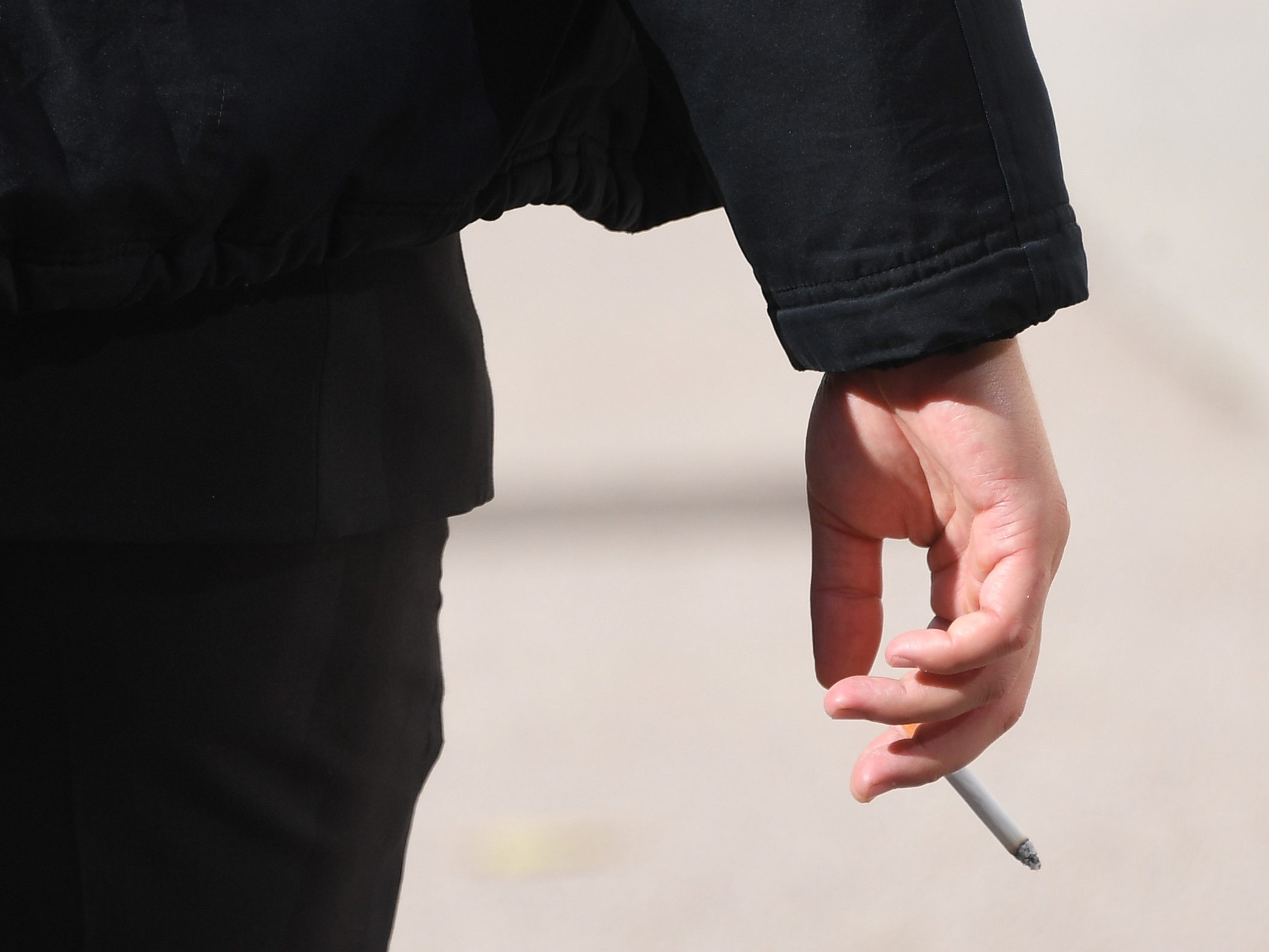 Eine Person mit einer Zigarette in der Hand.