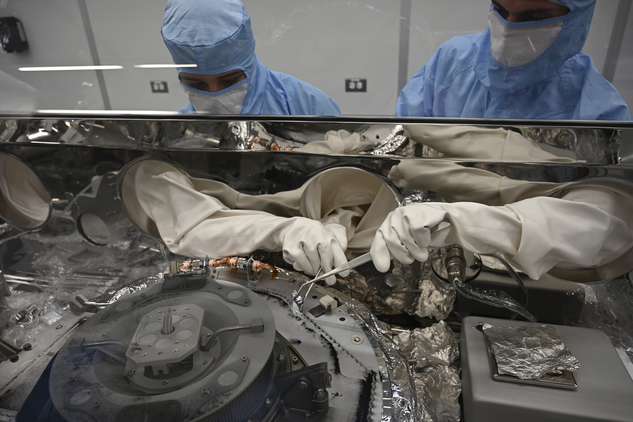 Auf diesem von der NASA bereitgestellten Foto sammeln Mari Montoya (links) und Curtis Calva am 27. September 2023 im Johnson Space Center in Houston mithilfe von Werkzeugen Asteroidenpartikel vom Boden eines Kanisters. Die Raumsonde Osiris-Rex lieferte eine Menge Trümmer, die vom Asteroiden Bennu gesammelt wurden. Auf diesem von der NASA bereitgestellten Foto sammeln Mari Montoya (links) und Curtis Calva am 27. September 2023 im Johnson Space Center in Houston mithilfe von Werkzeugen Asteroidenpartikel vom Boden eines Kanisters. Die Raumsonde Osiris-Rex lieferte eine Menge Trümmer, die vom Asteroiden Bennu gesammelt wurden.