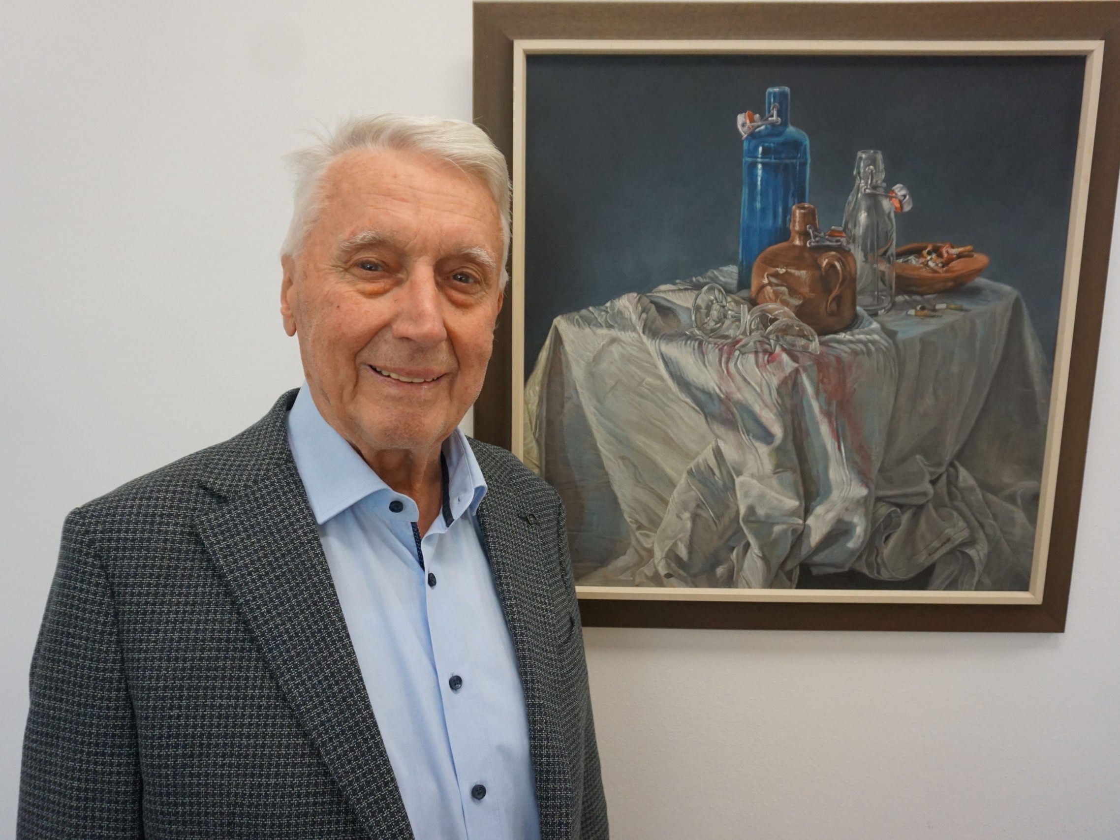 Alwin Rohner vor einem Stillleben von Eugen „Lucky“ Leitner, das auch die Einladung zur Ausstellung ziert.