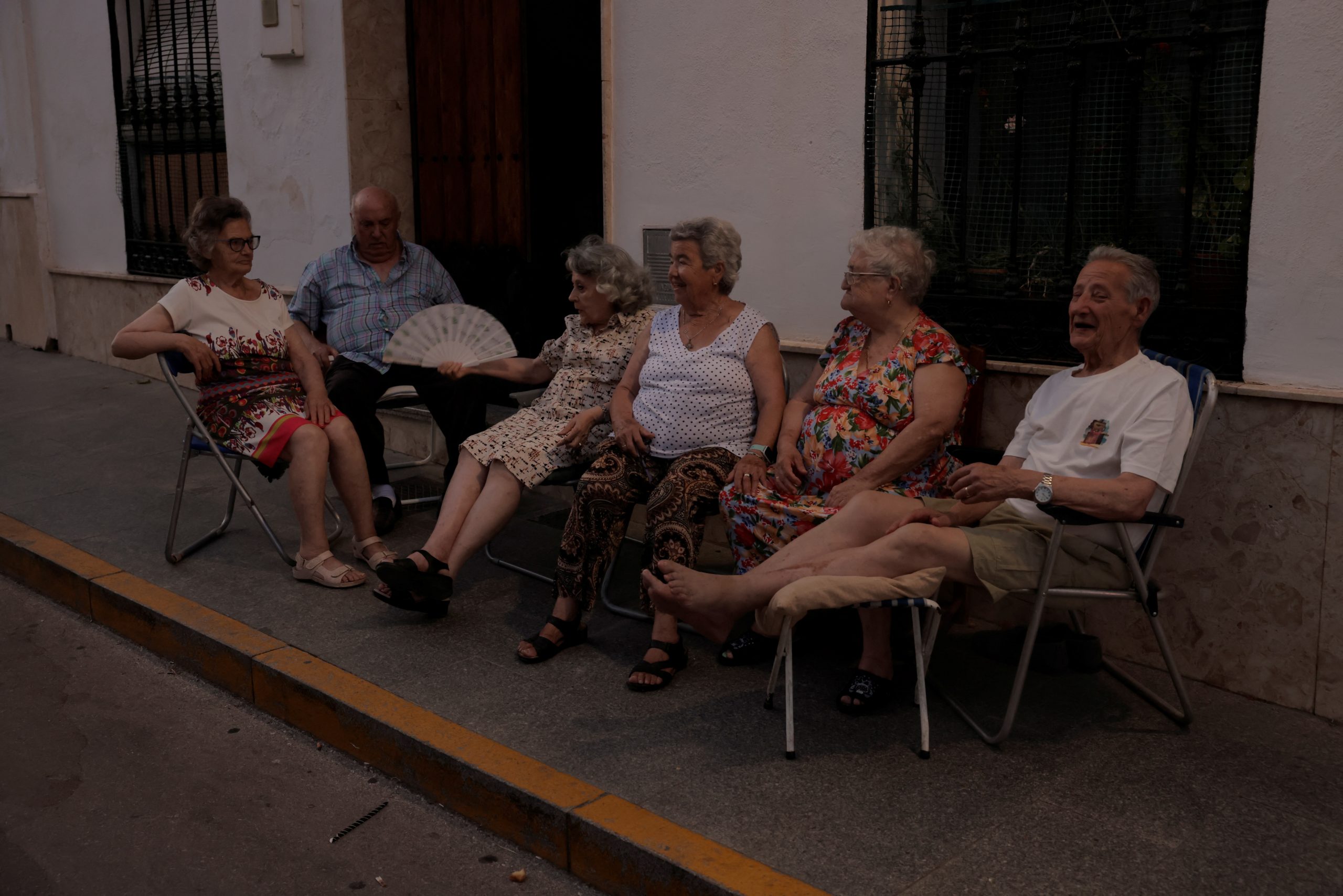 Nachbarn plaudern vor einem Haus, um der Hitze an einem heißen Sommerabend in Ronda zu entkommen.