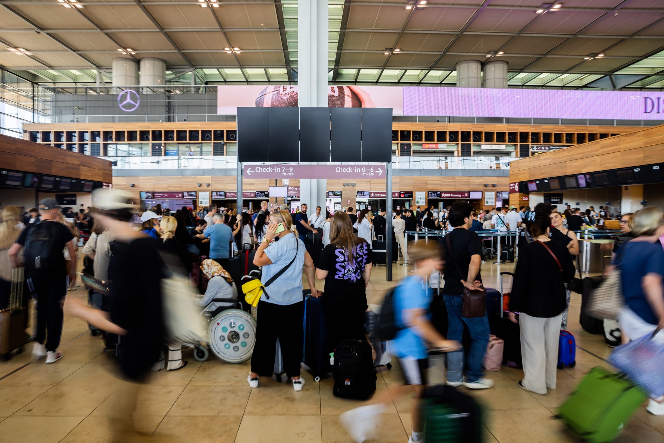 Zahlreiche Fluggäste warten am Hauptstadtflughafen BER vor einer schwarzen Anzeigetafel Zahlreiche Fluggäste warten am Hauptstadtflughafen BER vor einer schwarzen Anzeigetafel