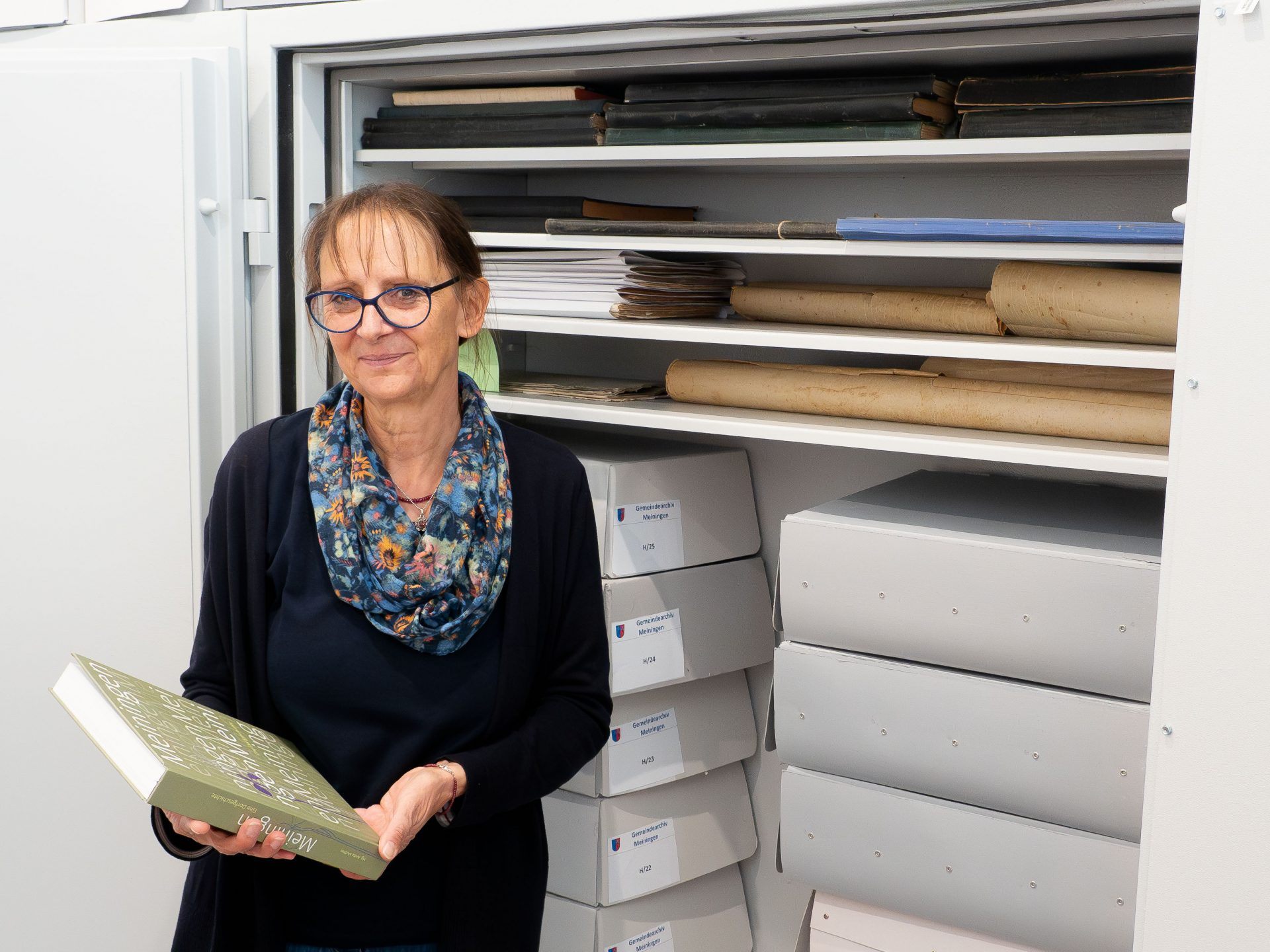 Die Archivarin Dr. Anita Muther mit ihrem Dorfgeschichte-Buch vor dem Stahlschrank mit besonders schützenswerter Archivalien.