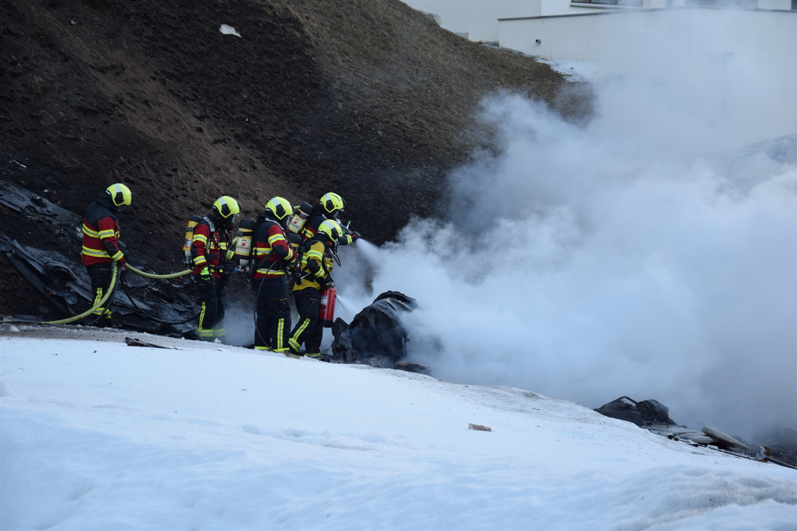 Feuerwehrleute löschen das brennende Wrack. Feuerwehrleute löschen das brennende Wrack.