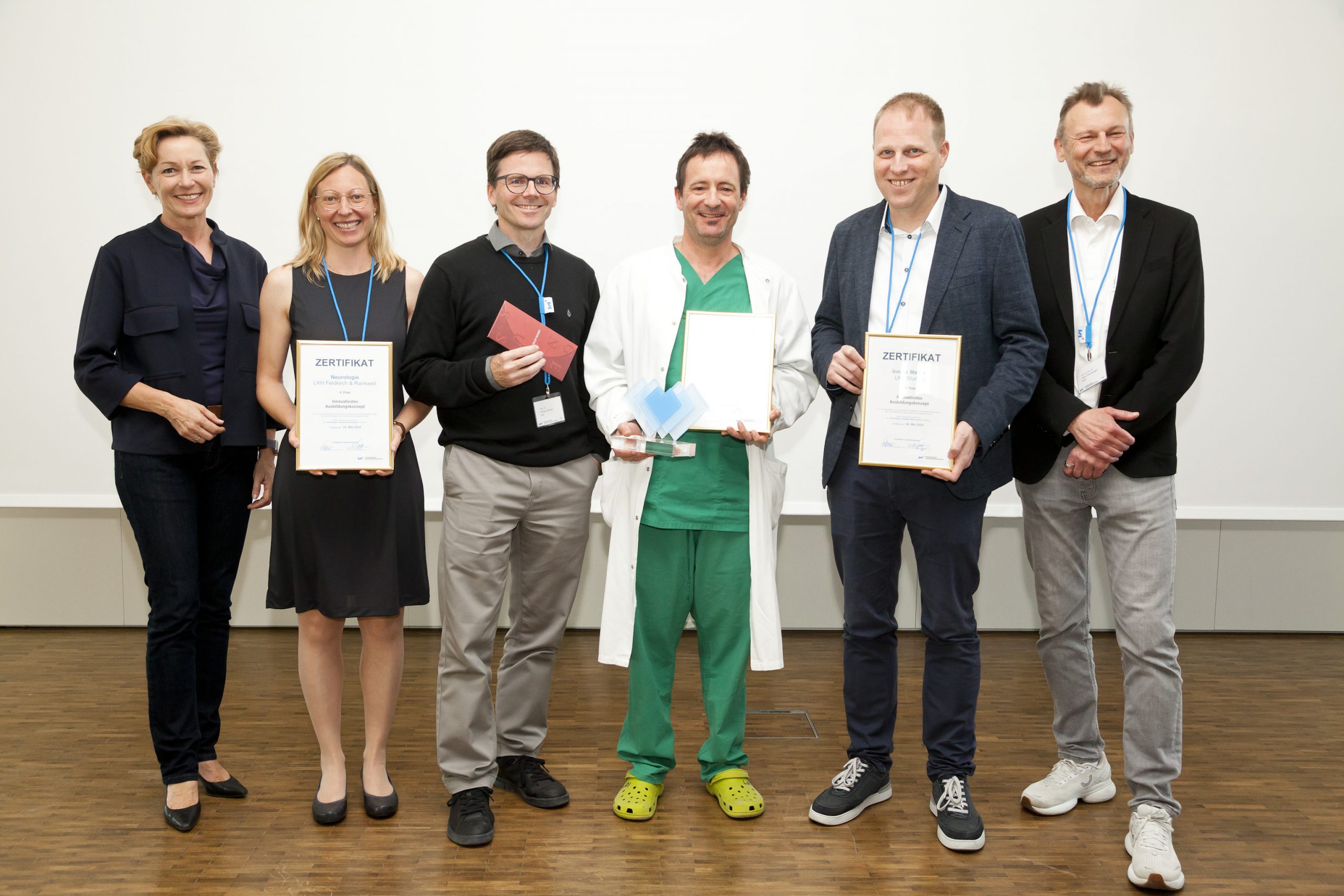 Glückliche Gewinner:innen: Sie haben das Zertifikat für eins der drei besten Ausbildungskonzepte 2025 in Vertretung für ihre Teams entgegengenommen, OÄ Dr. Julia Walch und Prim. Dr. Philipp Werner (Neurologie, LKH Feldkirch, Platz 2, 2.u.3.v.l.)), OA Dr. Alexander Loibnegger (Gefäßchirurgie, LKH Feldkirch, Platz 1, Mitte), Chefarzt Prim. Dr. Alois Süssenbacher (LKH Bludenz, Innere, Platz 3, 2.v.r.). Ganz links: Landesrätin Martina Rüscher, ganz rechts Dir. Priv.-Doz. Peter Fraunberger, Geschäftsführer KHBG. Glückliche Gewinner:innen: Sie haben das Zertifikat für eins der drei besten Ausbildungskonzepte 2025 in Vertretung für ihre Teams entgegengenommen, OÄ Dr. Julia Walch und Prim. Dr. Philipp Werner (Neurologie, LKH Feldkirch, Platz 2, 2.u.3.v.l.)), OA Dr. Alexander Loibnegger (Gefäßchirurgie, LKH Feldkirch, Platz 1, Mitte), Chefarzt Prim. Dr. Alois Süssenbacher (LKH Bludenz, Innere, Platz 3, 2.v.r.). Ganz links: Landesrätin Martina Rüscher, ganz rechts Dir. Priv.-Doz. Peter Fraunberger, Geschäftsführer KHBG.