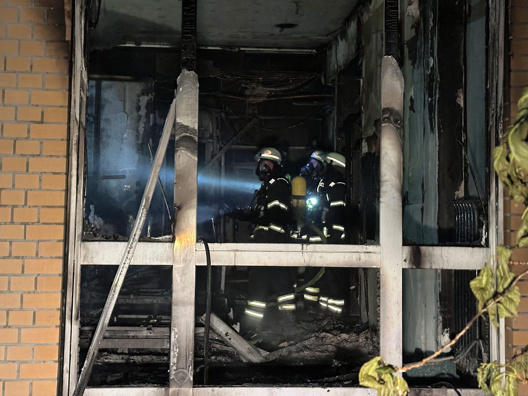 Feuerwehrleute mit Atemschutzgerät arbeiten in einem ausgebrannten Raum im Erdgeschoß im Marienkrankenhaus im Hamburger.