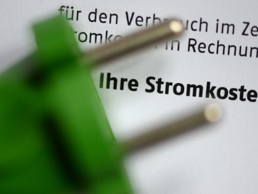 Auf dem Bild sieht man ein Stück eines Steckers auf einer Stromrechnung liegen. Man kann das Wort "Stromkosten" lesen.