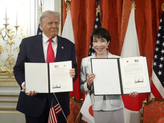 Auf dem Bild sieht man US-Präsident Donald Trump und die japanische Regierungschefin Sanae Takaichi. Sie halten ein unterschriebenes Abkommen in der Hand.