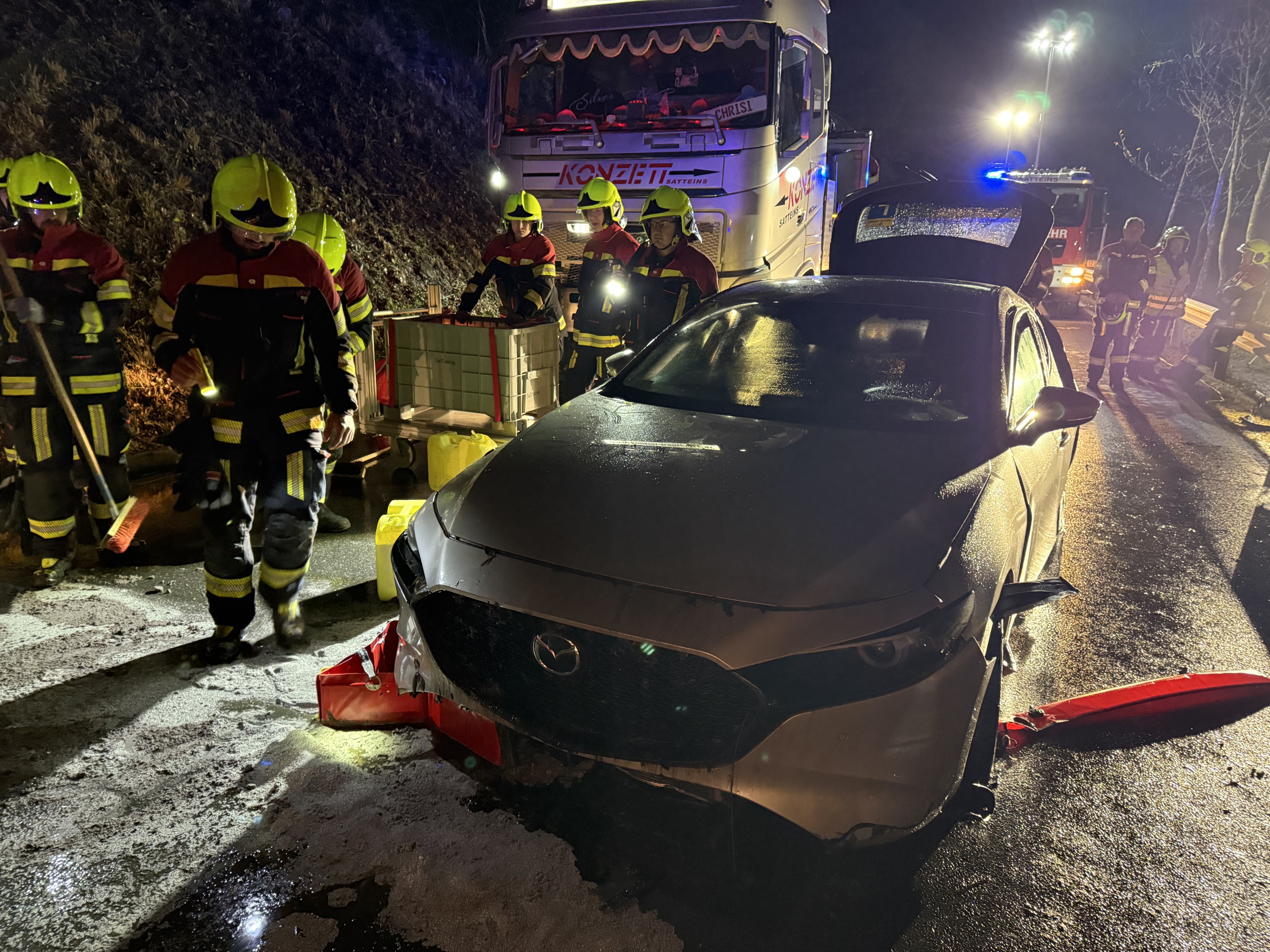 Feuerwehrleute sichern das geborgene Fahrzeug und binden ausgetretene Betriebsmittel.