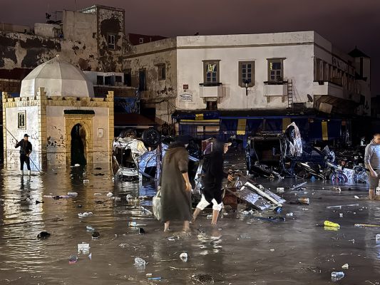 Menschen waten in der Hafenstadt Safi über einen überfluteten Platz