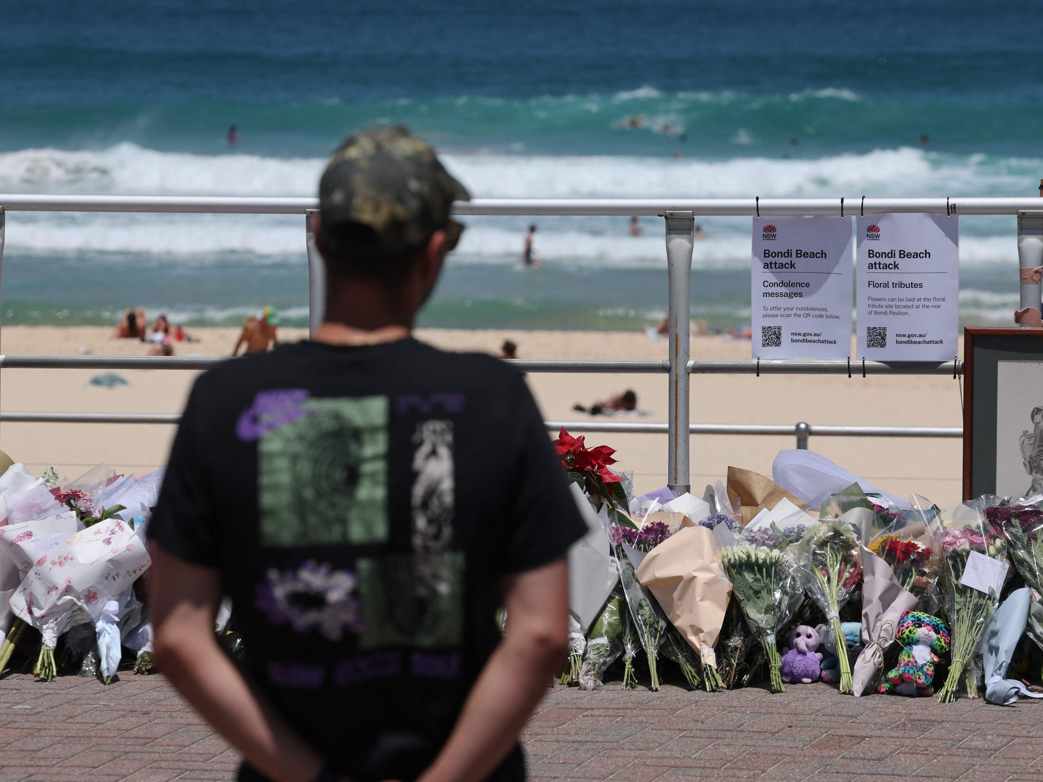 Ein Mann betrachtet abgelegte Blumen am Anschlagsort.