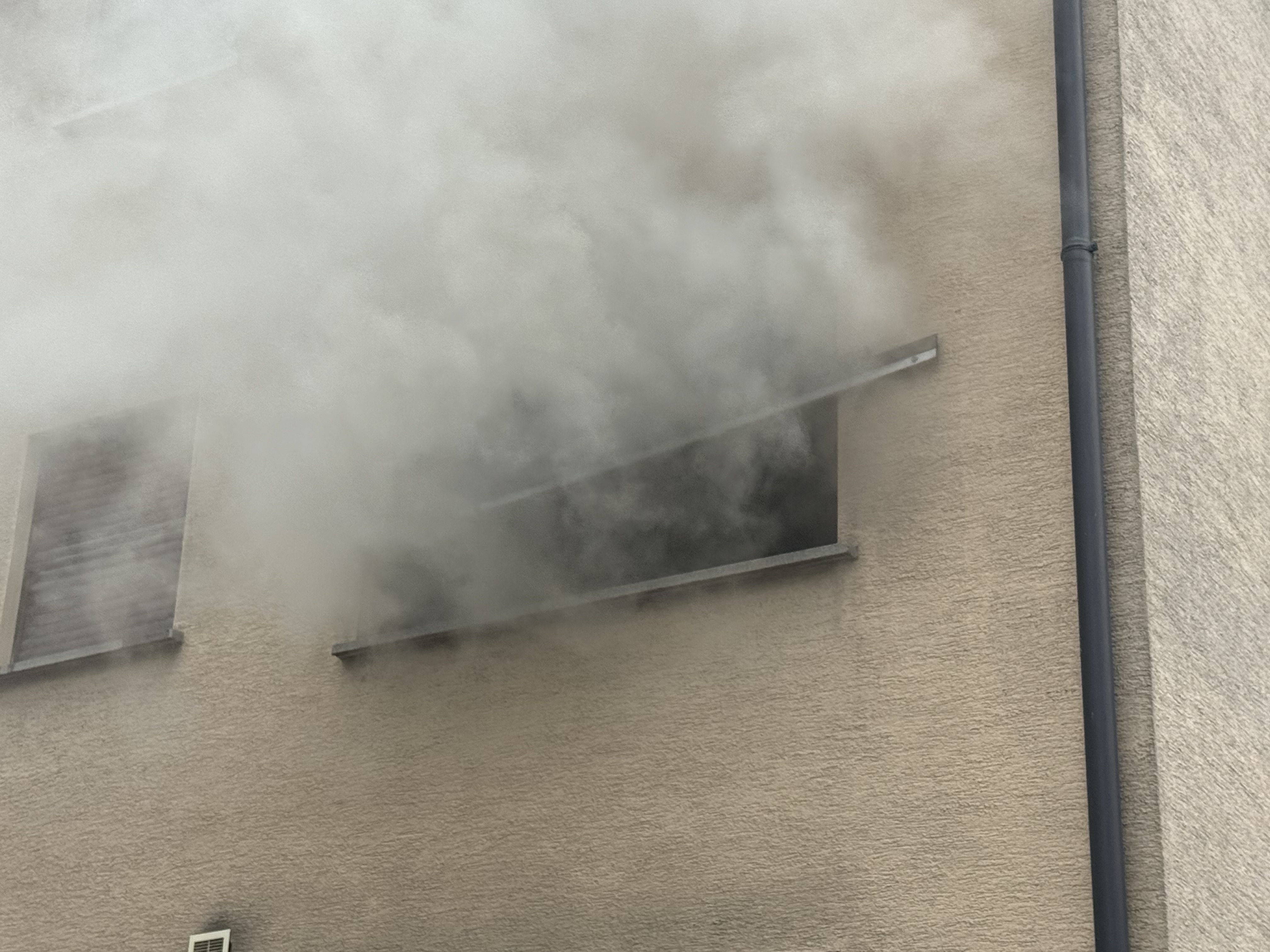 Dichter Rauch dringt aus einem Fenster im oberen Stockwerk der Wohnanlage. 
